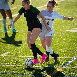 Female soccer player dribbling ball in pink shoes